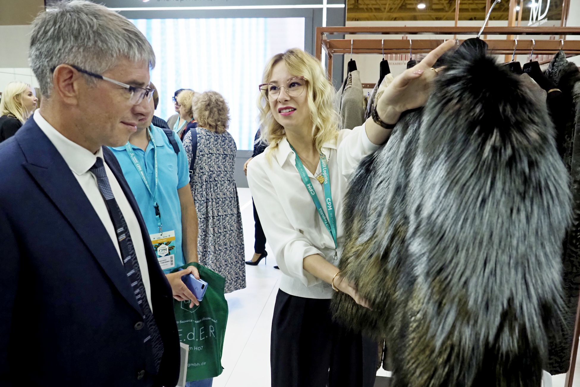 Представитель столичного дома одежды Екатерина Карцева показывает шубу из зимней коллекции на стенде Made in Moscow руководителю Департамента предпринимательства и инновационного развития Москвы Алексею Фурсину