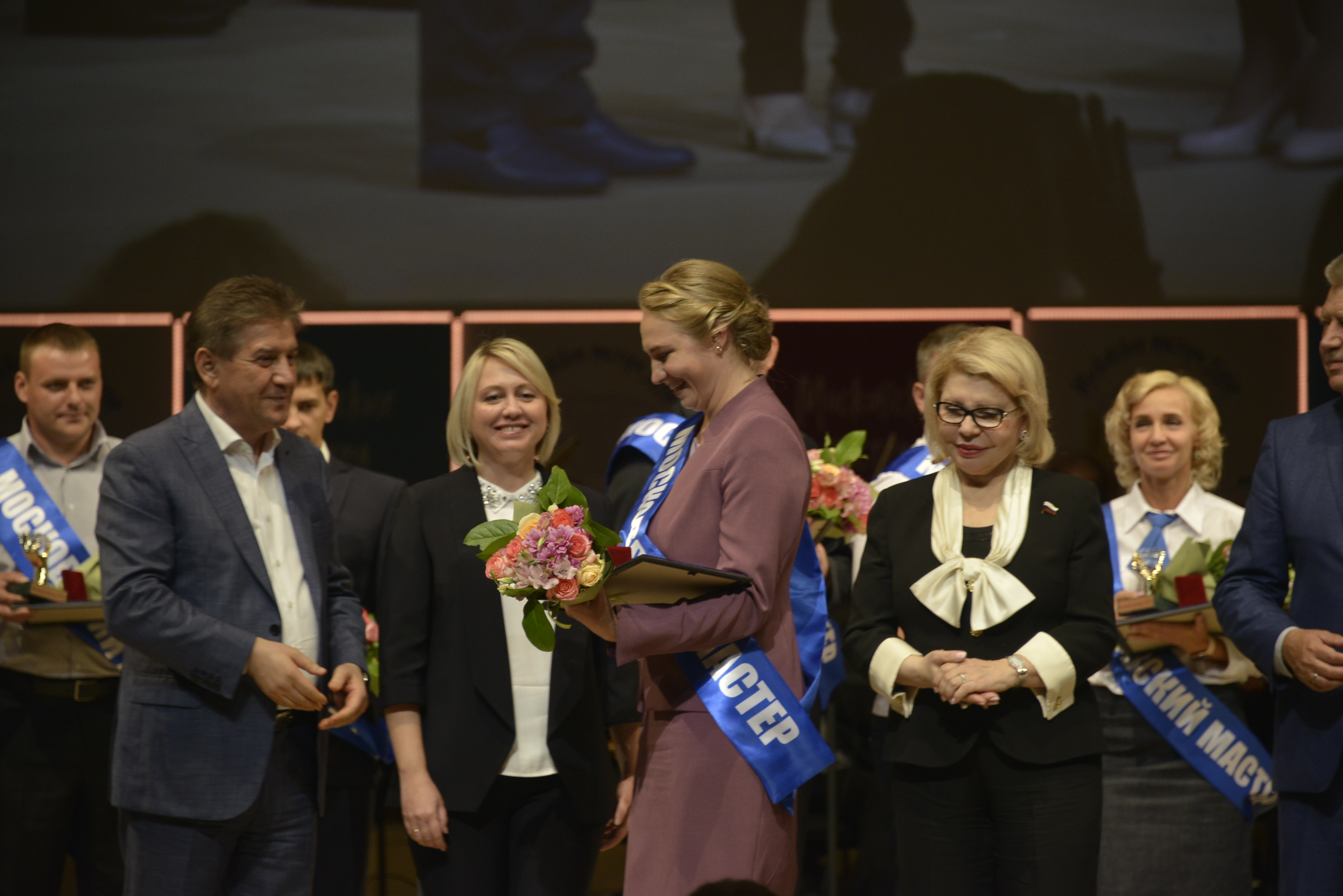 Министр правительства Москвы, глава Департамента труда и социальной защиты населения Владимир Петросян и председатель Комитета общественных связей и молодежной политики столицы Екатерина Драгунова (в центре) награждают лучшего специалиста органов ЗАГС Светлану Пахомову