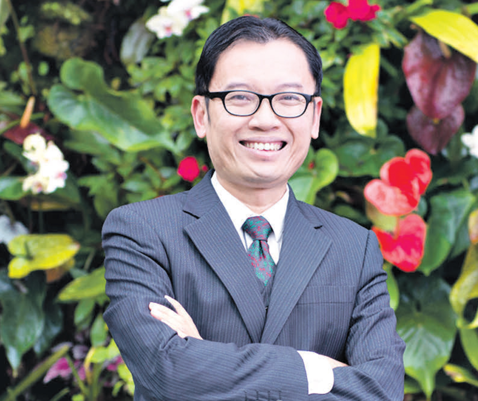 Директор всемирно известного сингапурского парка «Сады у Залива» Феликс Ло позирует для фотографа на фоне цветочной композиции тропических растений