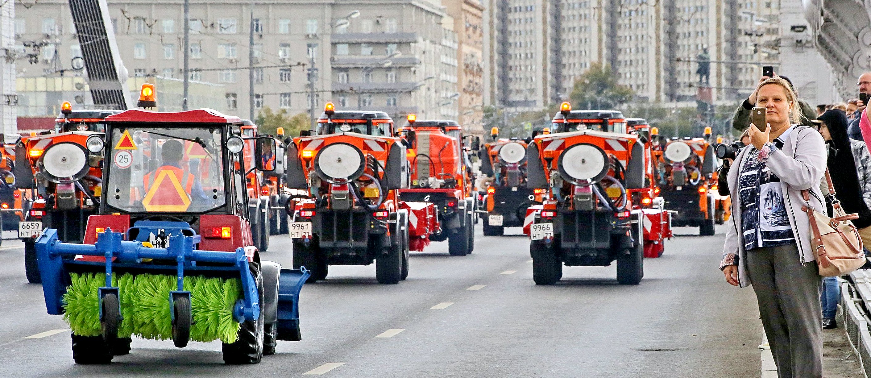 Уборочные машины в колонне коммунальной техники проходят парадом по Садовому кольцу, привлекая внимание прохожих