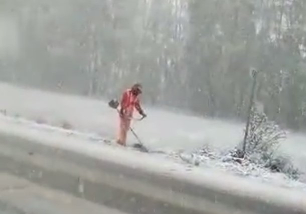 Работник коммунальных служб вышел косить траву в снегопад