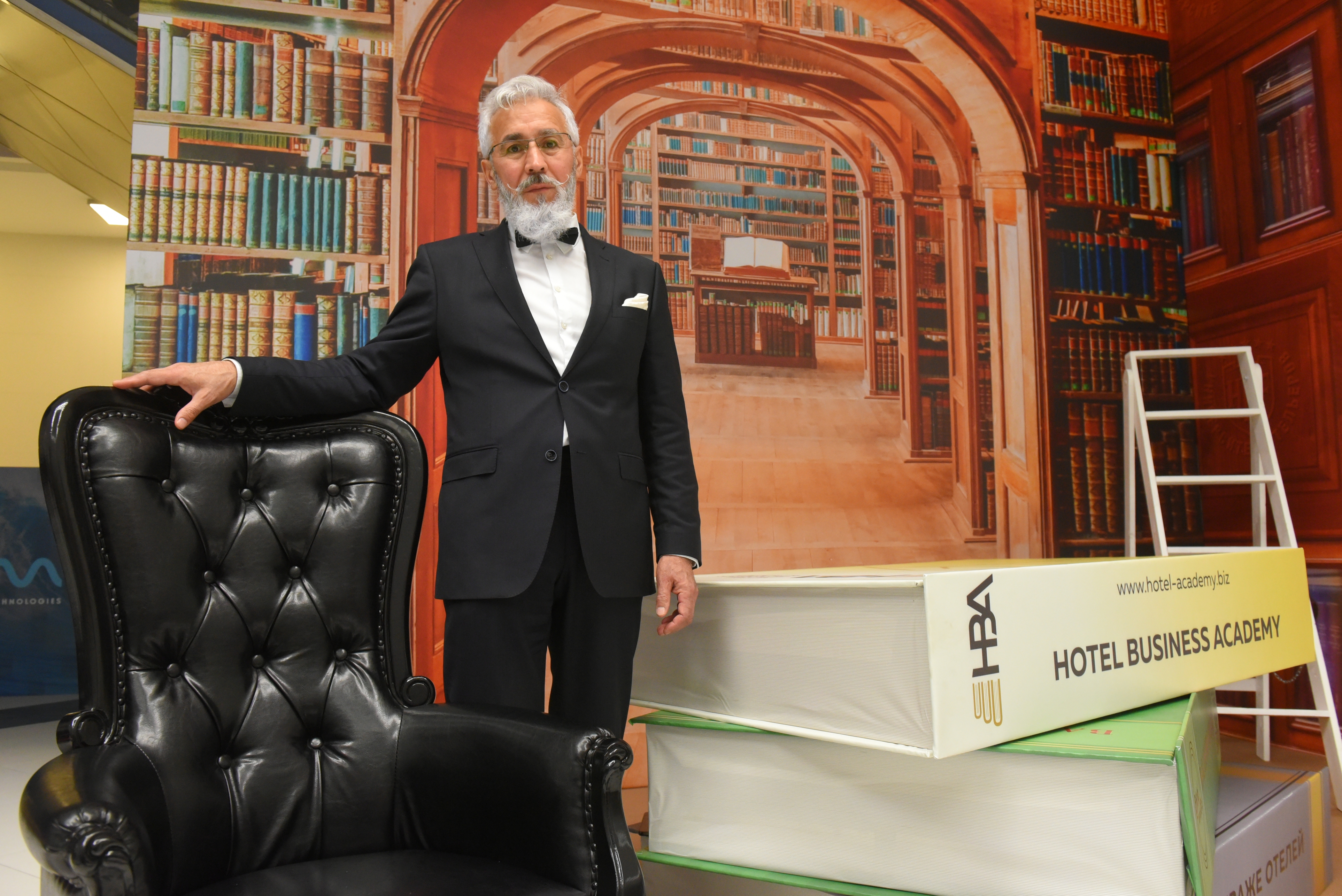 Один из гостей форума, Эльдар Аттила, в фотозоне, изображающей интерьеры университетской библиотеки. Темой форума в этом году стал университет отельеров