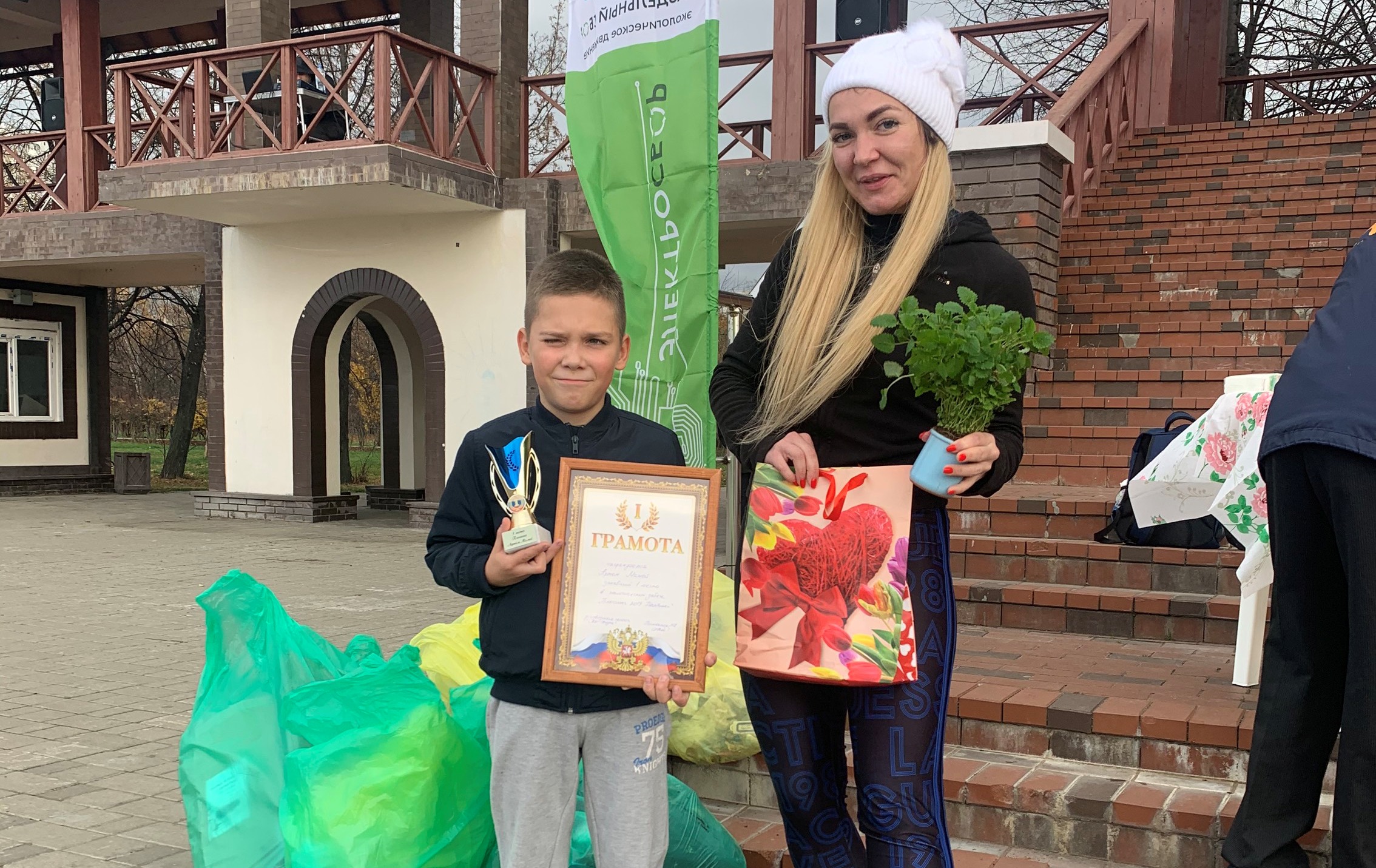 Мария Томенюк награждает победителя пробежки чистоты в парке «Печатники» Артема Мамея
