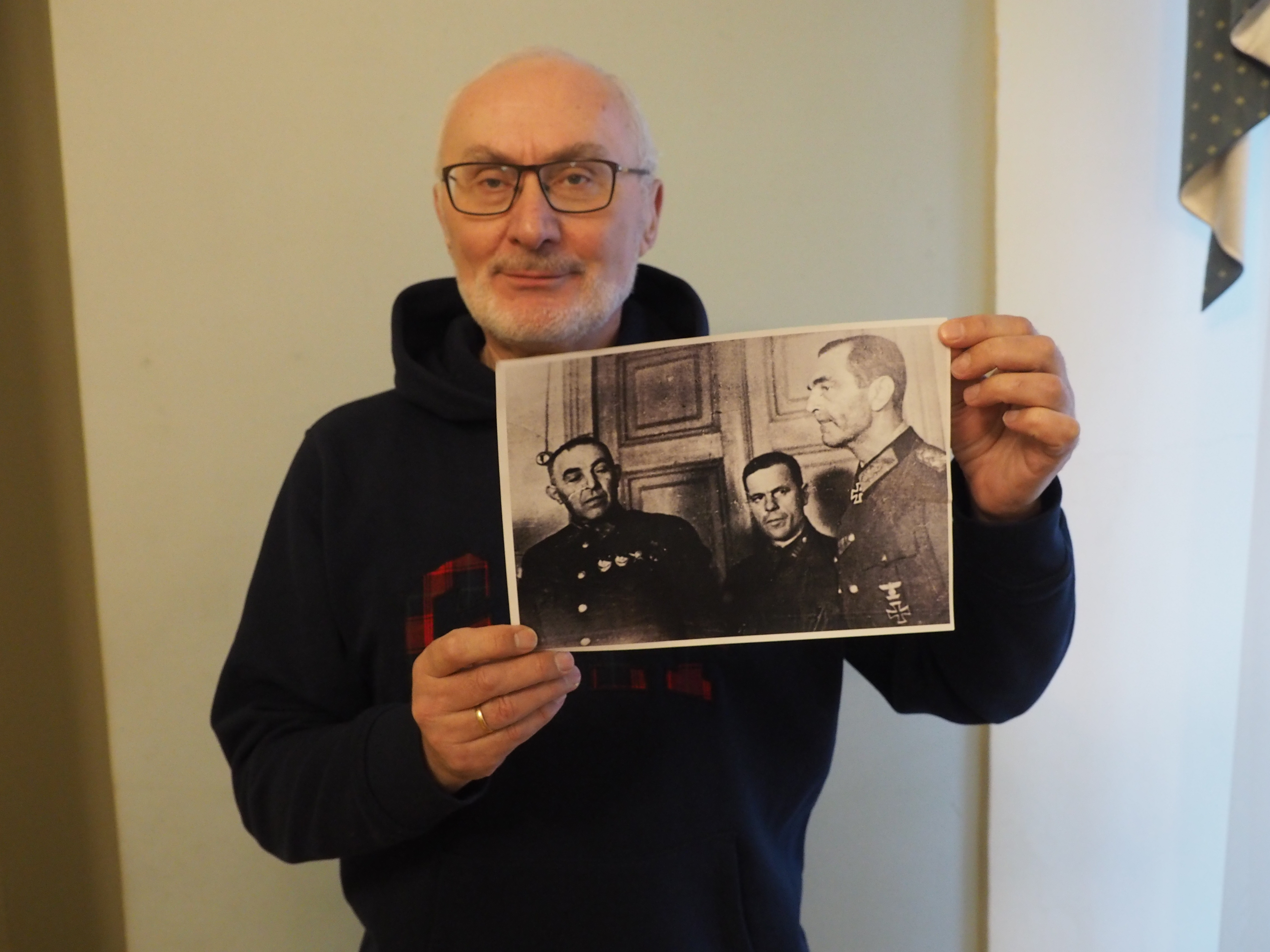 Юрий Трубников держит фото, на котором запечатлены (слева направо) его дед Кузьма Трубников, политрук Леонид Винокур и пленный фельдмаршал Паулюс