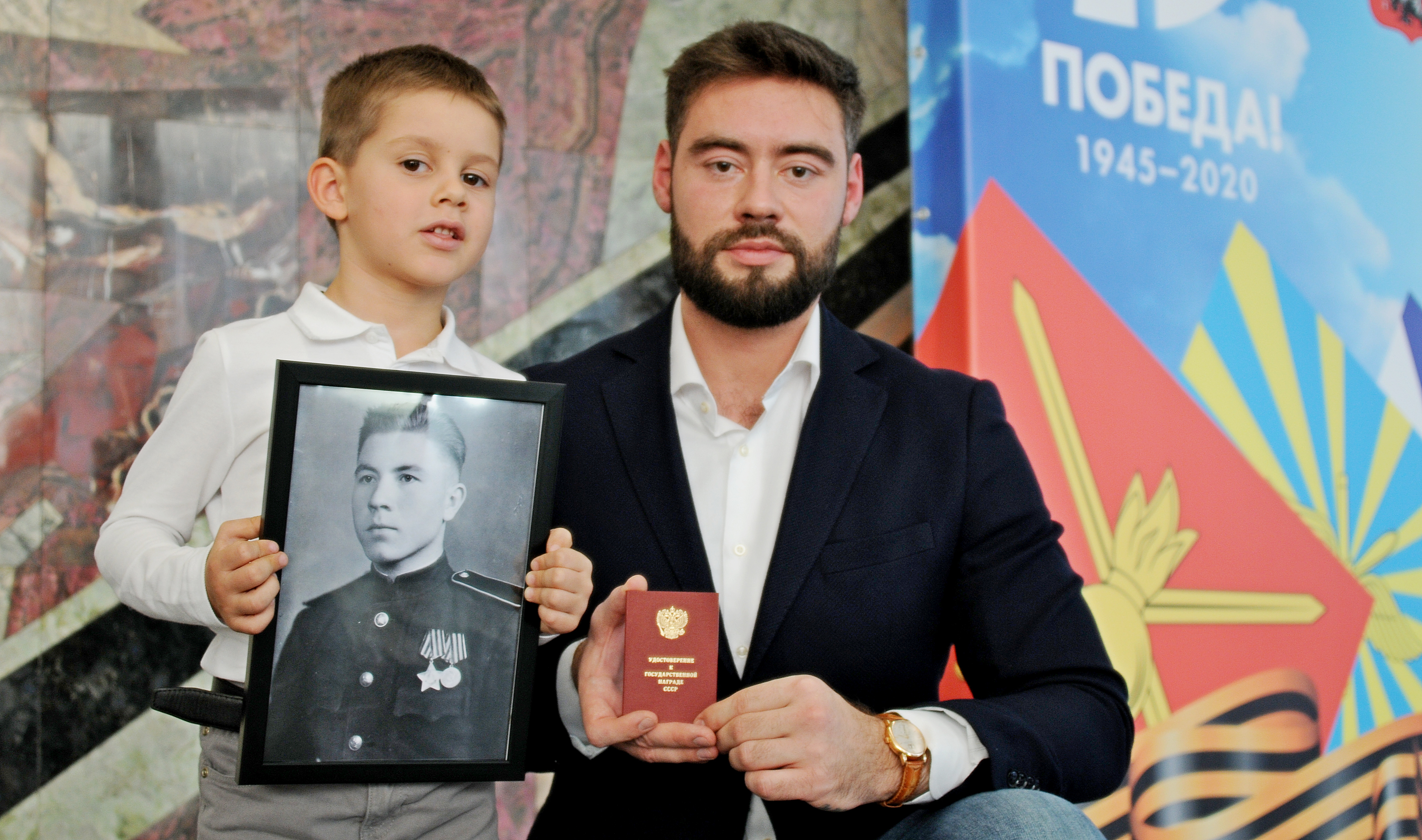 Правнук Михаила Коломийца Федор Сердюк (слева) вместе с дядей, Алексеем Коломийцем, получили удостоверение к медали «За отвагу» на своего предка — участника Великой Отечественной войны Михаила Коломийца. В руках четырехлетнего Феди — портрет отважного предка 