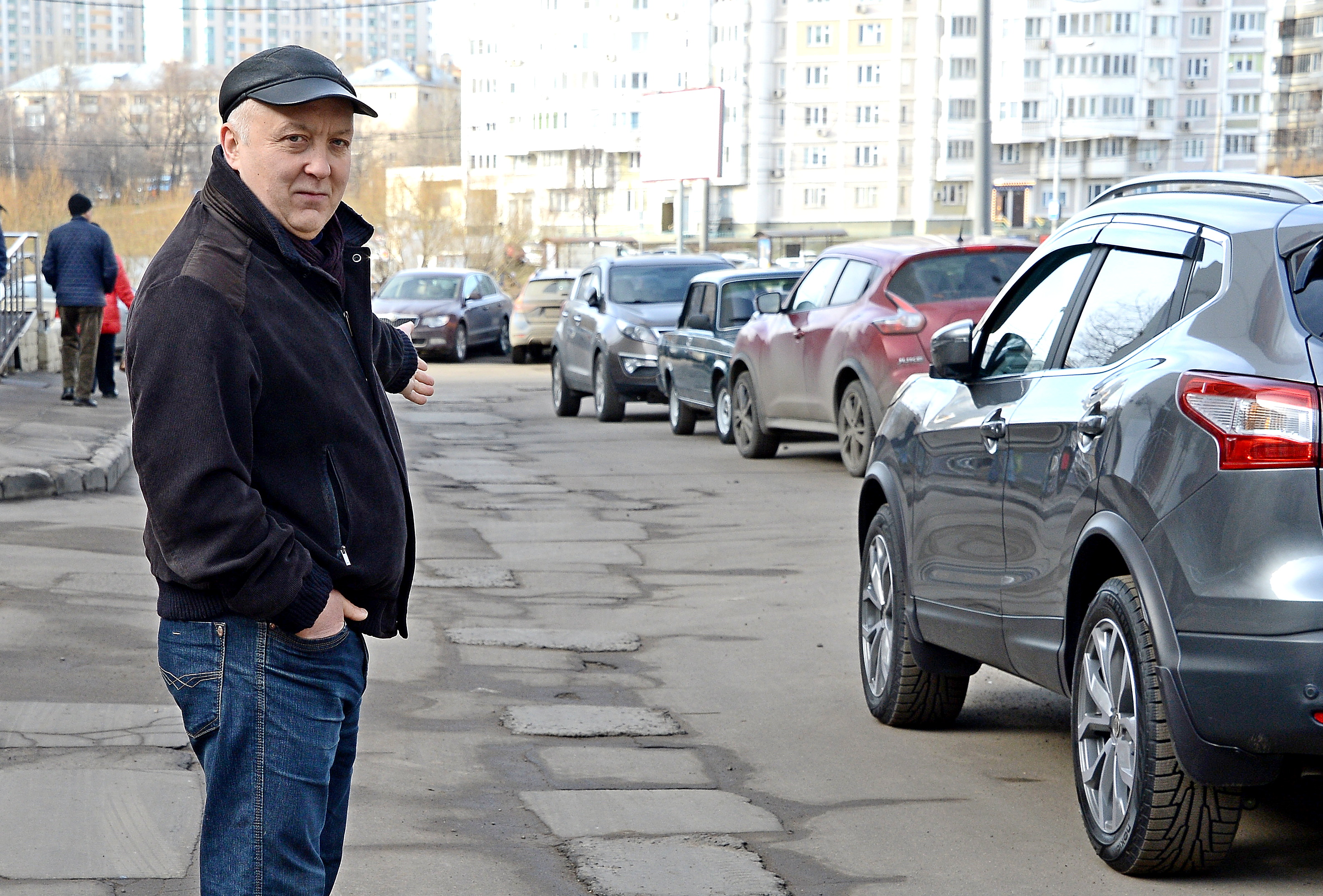 Москвич Сергей Марьин показывает участок дороги неподалеку от своего дома, где почти каждый месяц появляются новые асфальтовые заплатки