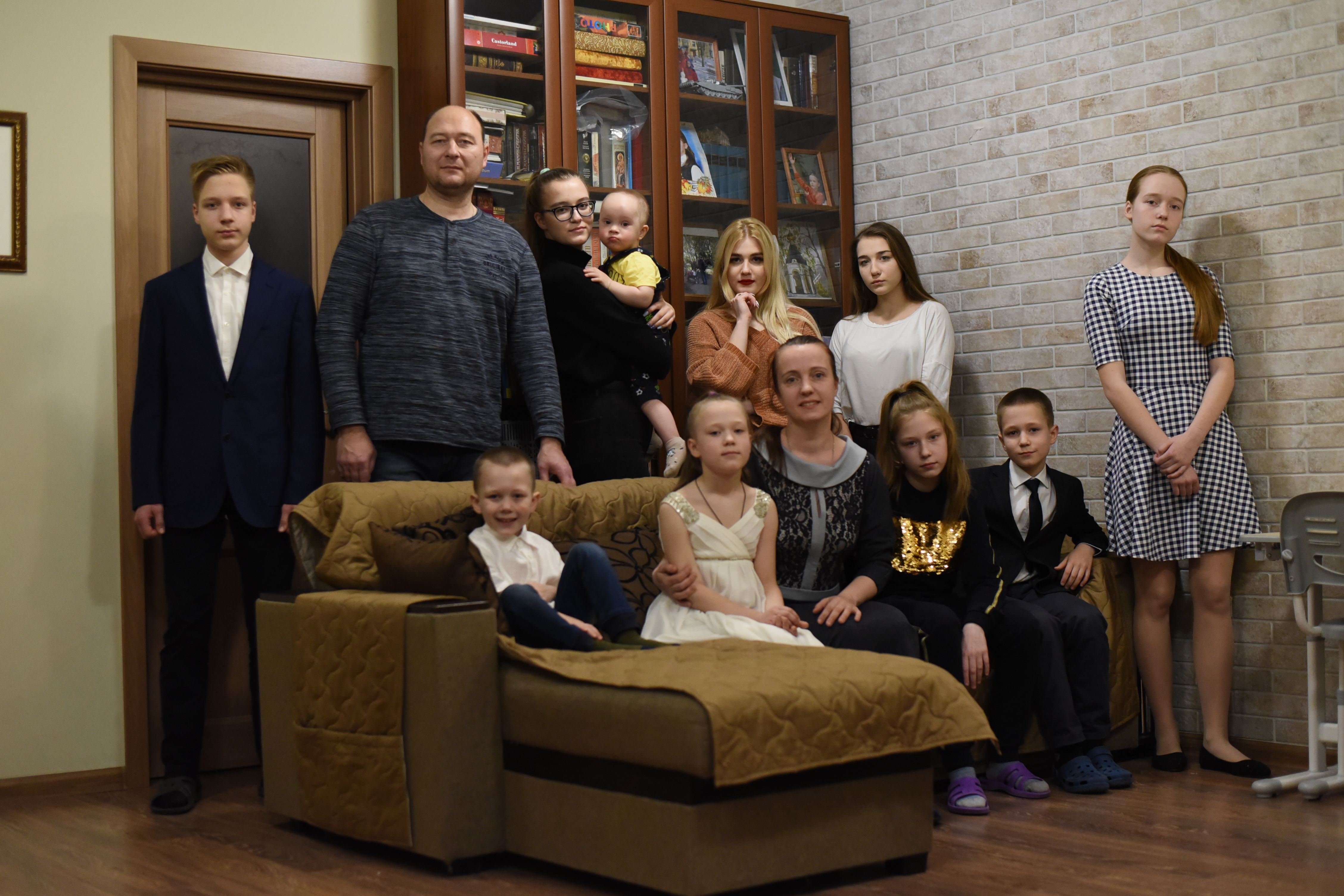 Семья Малкиных в гостиной своего большого уютного дома (слева направо): Иван, папа Олег, Таня с Дани- илом на руках, Настя, Маша и Лена (стоят). На диване — Дима, Александра, мама Ольга, Люба и Алексей