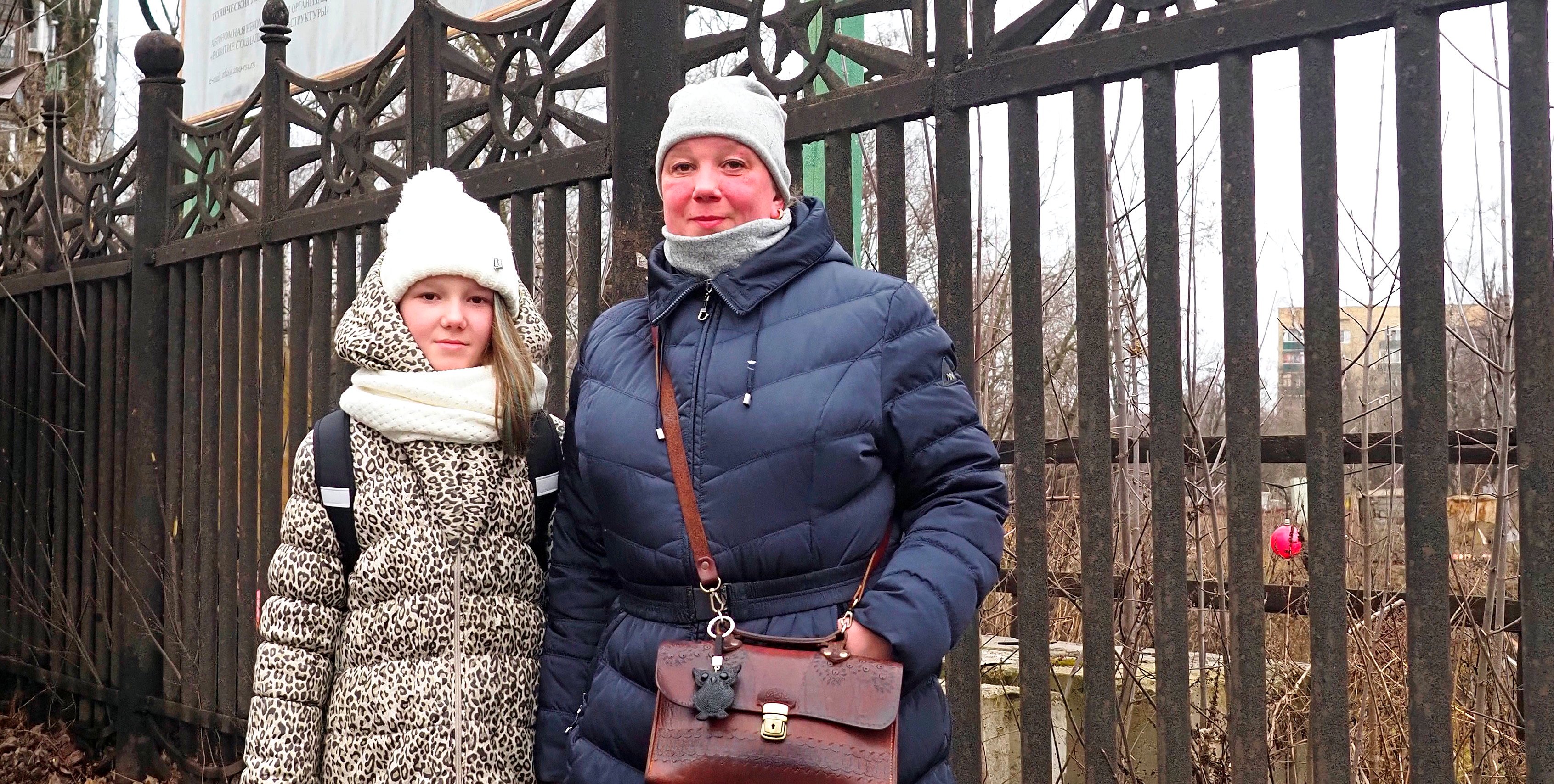 Надежда Софонцева вместе с дочкой Полиной ждут автобуса возле обнесенного забором котлована. Именно тут, если верить информации на баннере, в 2022 году должна появиться новая поликлиника