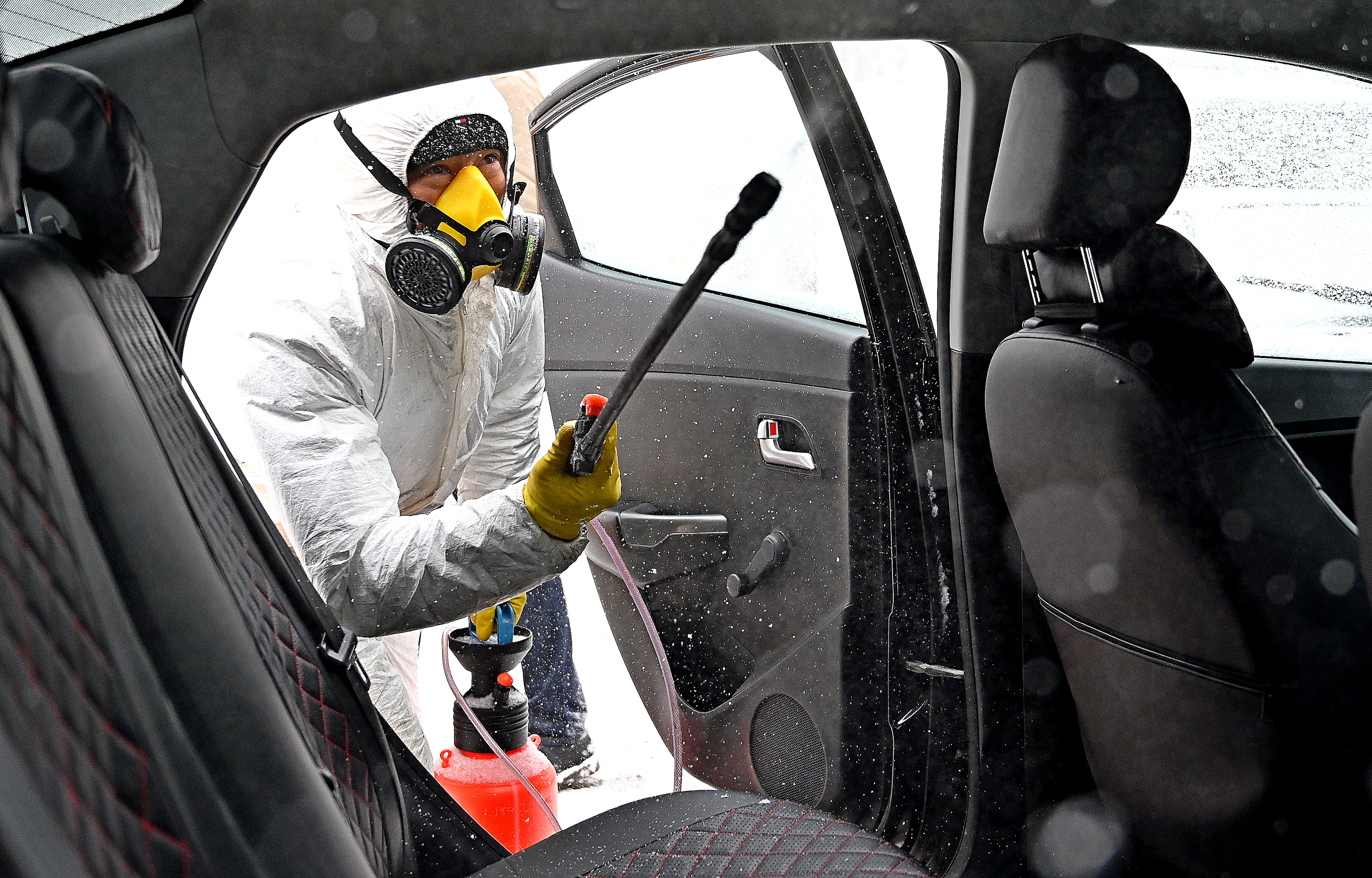 Андрей Абдувахидов обрабатывает салон автомобиля, который прибыл на стационарный пункт дезинфекции такси