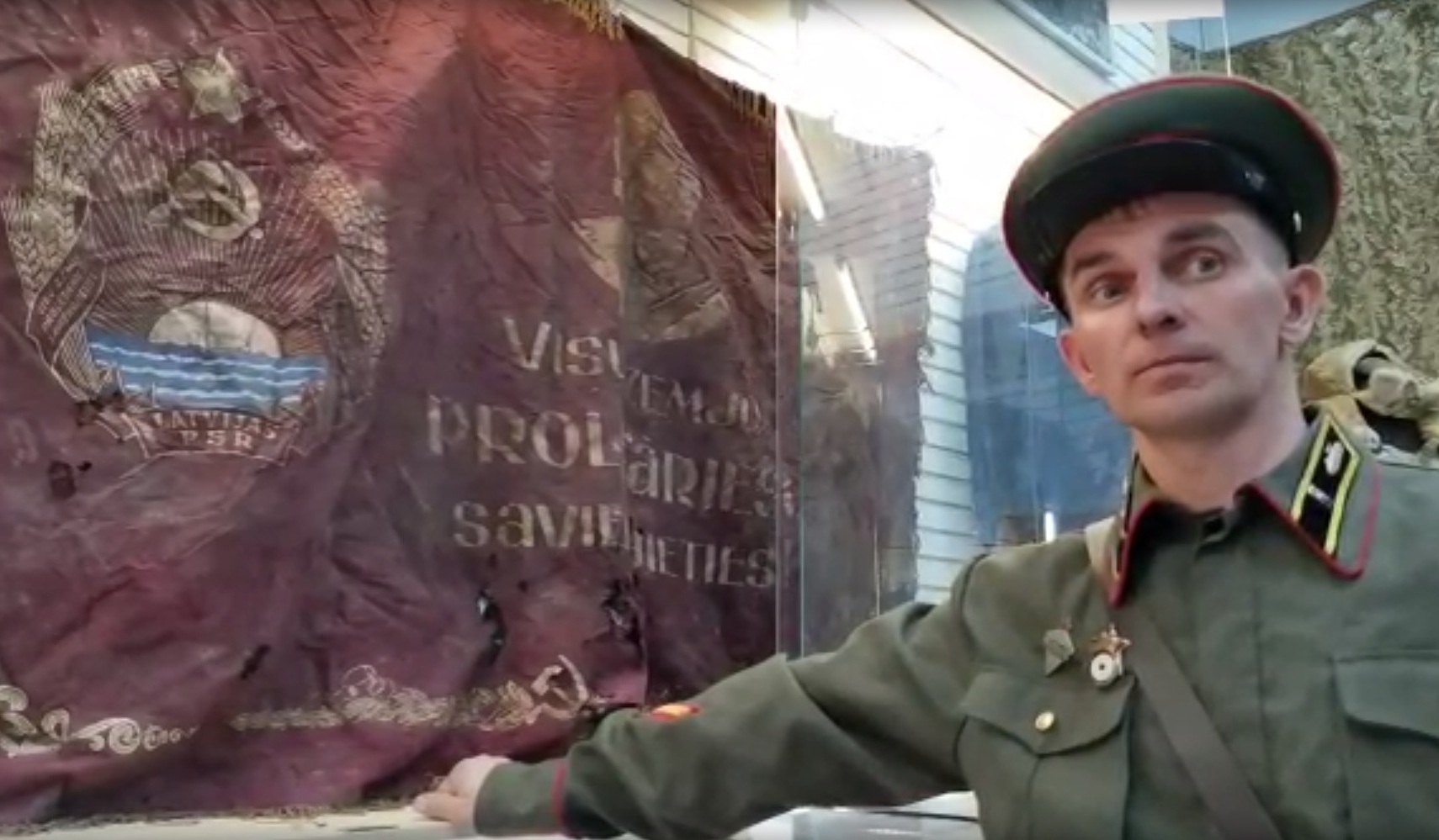 Руководитель поискового отряда «Славный» Иван Сопов в форме красноармейца рядом с найденным знаменем 