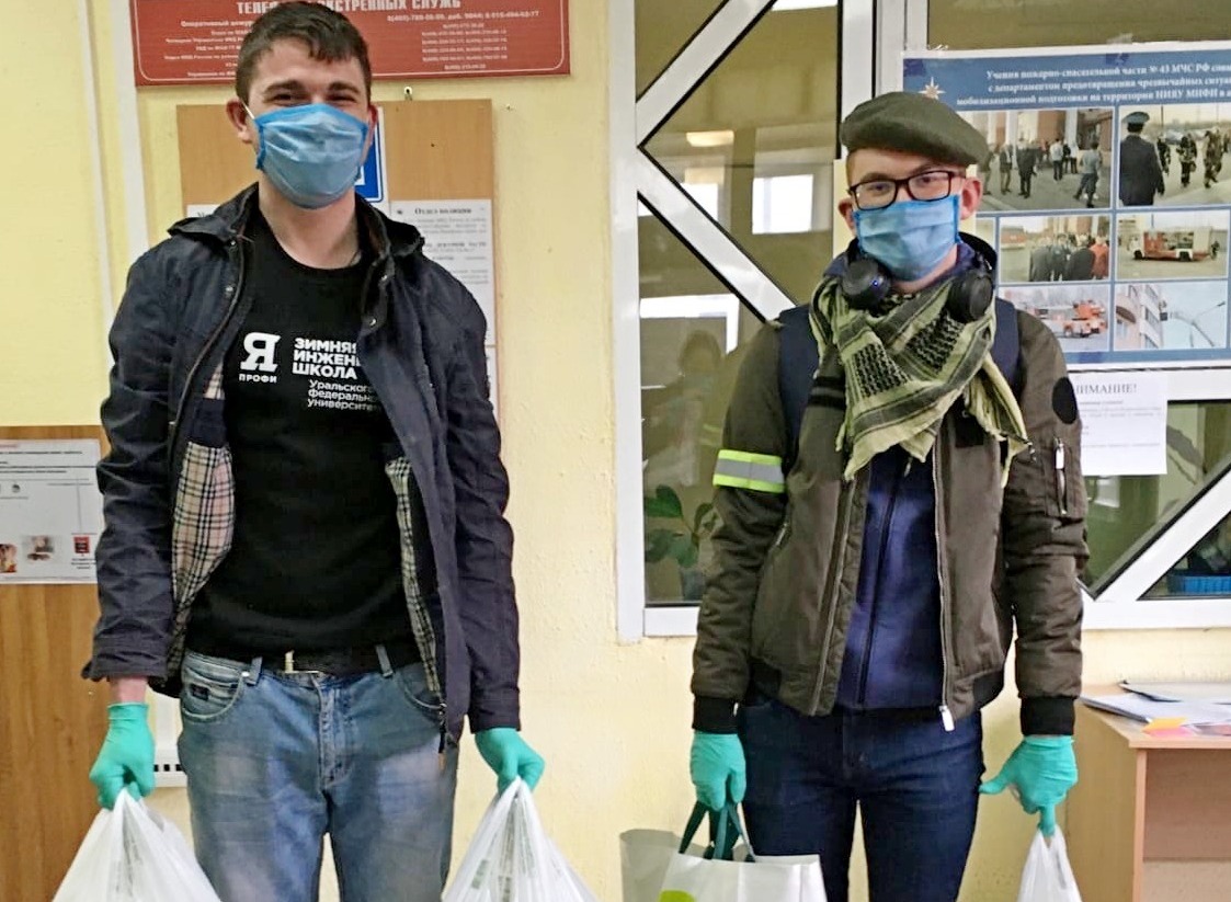 Волонтеры Владимир Чурсин (слева) и Никита Тачкин разносят пакеты с продуктами по комнатам