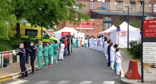 Врачи и медсестры выстроились по обе стороны асфальтовой дорожки, которая ведет к больнице