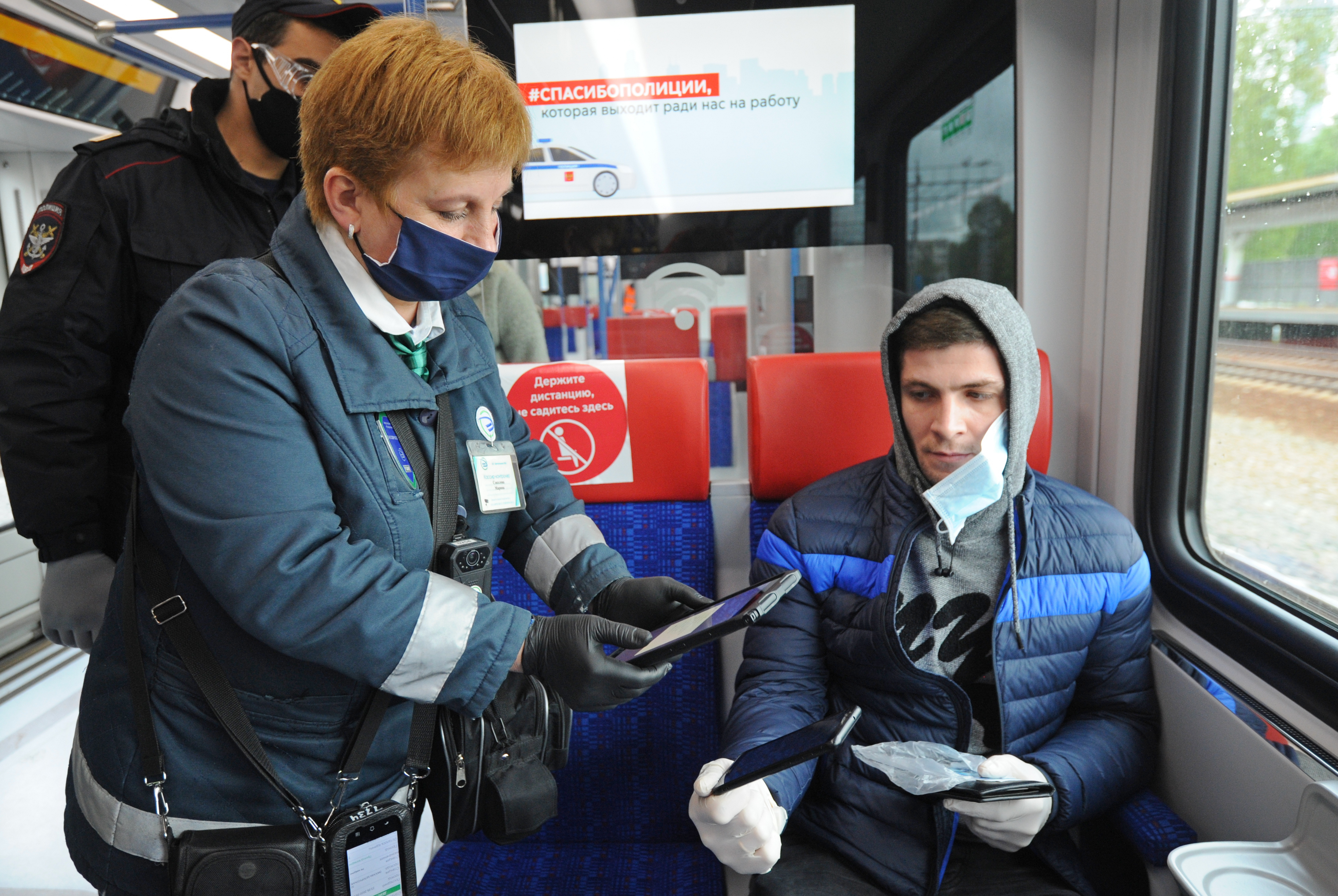 Сотрудник полиции Гарик Тумасян и контролер Марина Соколова проверяют цифровой пропуск, а также наличие маски и перчаток у пассажира МЦД-1 «Одинцово — Лобня» Тиграна Хистова