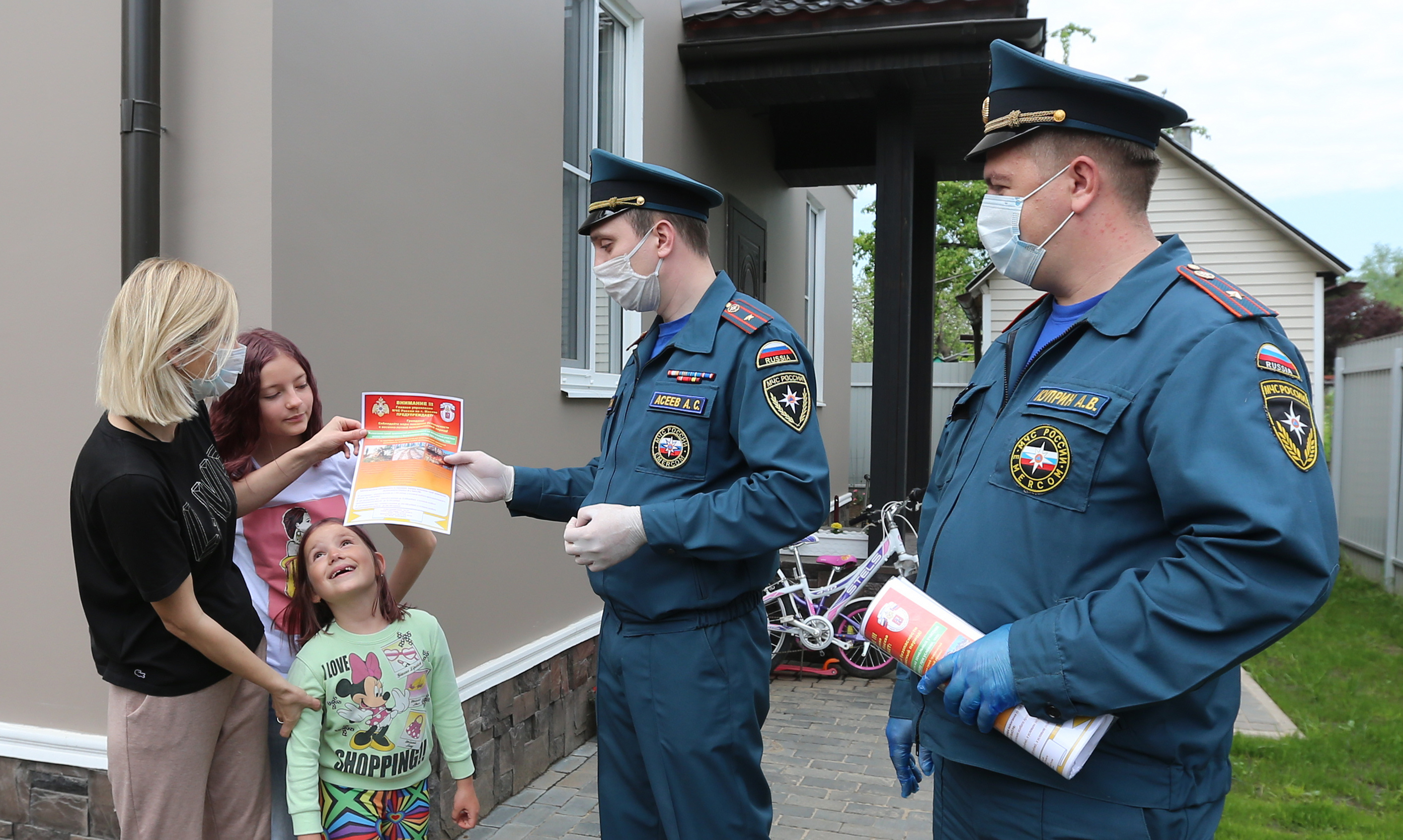 Сотрудники Управления МЧС по ТиНАО Александр Асеев (в центре) и Андрей Куприн проводят профилактическую беседу с Татьяной Пройдисвет и вручают ей и ее дочерям, старшей Ульяне и маленькой Арине, листовку с информацией о пожарной безопасности