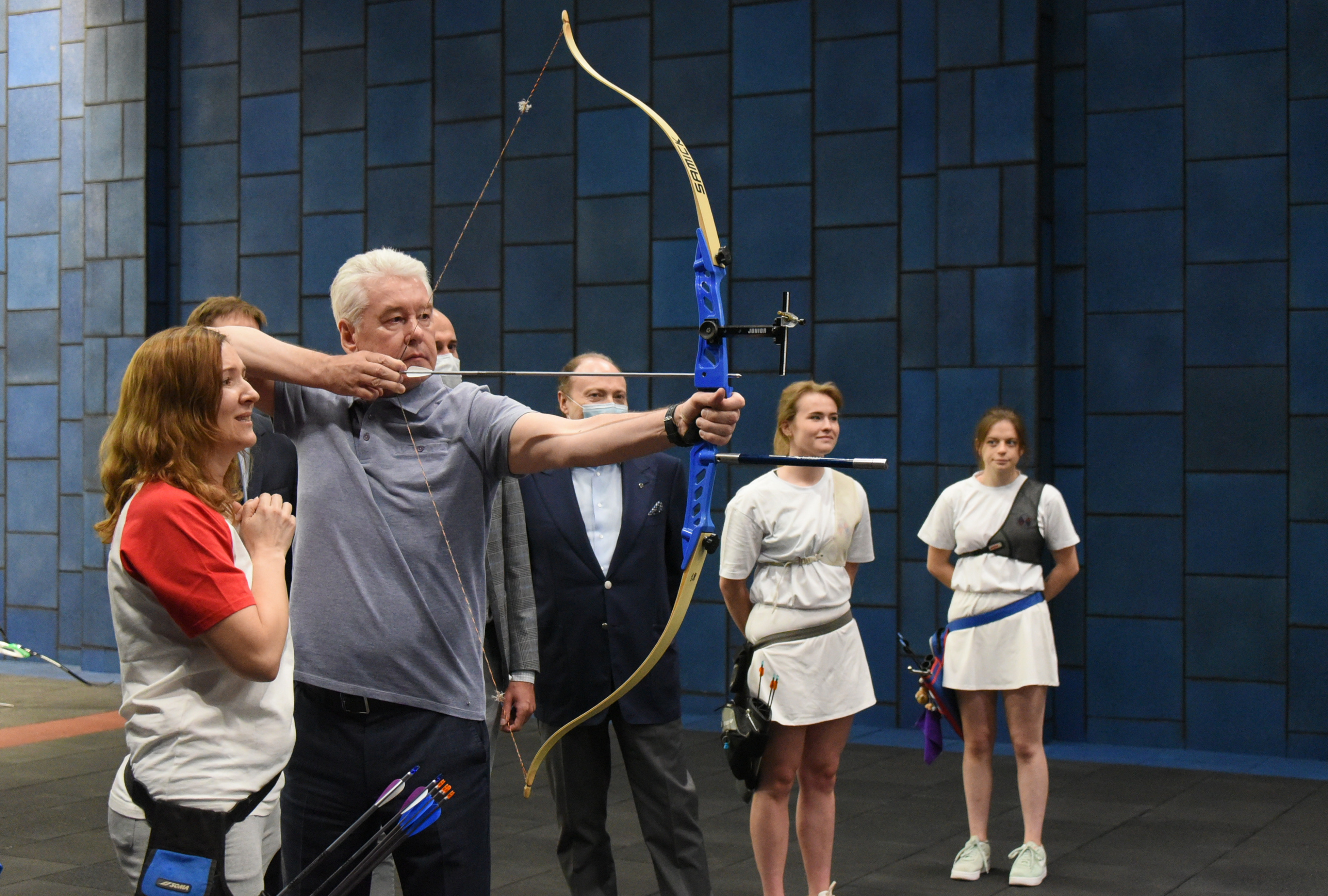 Мэр Москвы Сергей Собянин (второй слева) под руководством мастера спорта международного класса, чемпионки России Татьяны Кирочкини (крайняя слева), тренируется в стрельбе из лука в тире нового Центра современного пятиборья