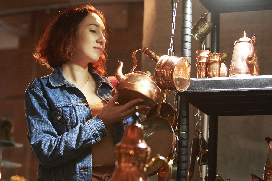 Москвичка Мария Неседина рассматривает старинную медную посуду, которую можно приобрести на блошином рынке