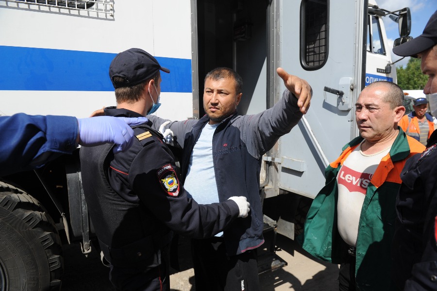 Младший сержант полиции Сергей Кудряшев досматривает гражданина Узбекистана Михредина Раджабова (в центре) перед посадкой в автозак. Своей очереди ждет его соотечественник Фарход Кулдашев. Мигранты нарушили правила пребывания в Российской Федерации