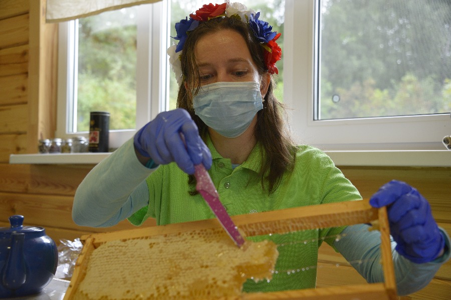 Участница праздника «Медовый Спас» в Бирюлевском дендропарке Ольга Мирзаева показывает гостям пчелиные соты, заполненные первым летним медом