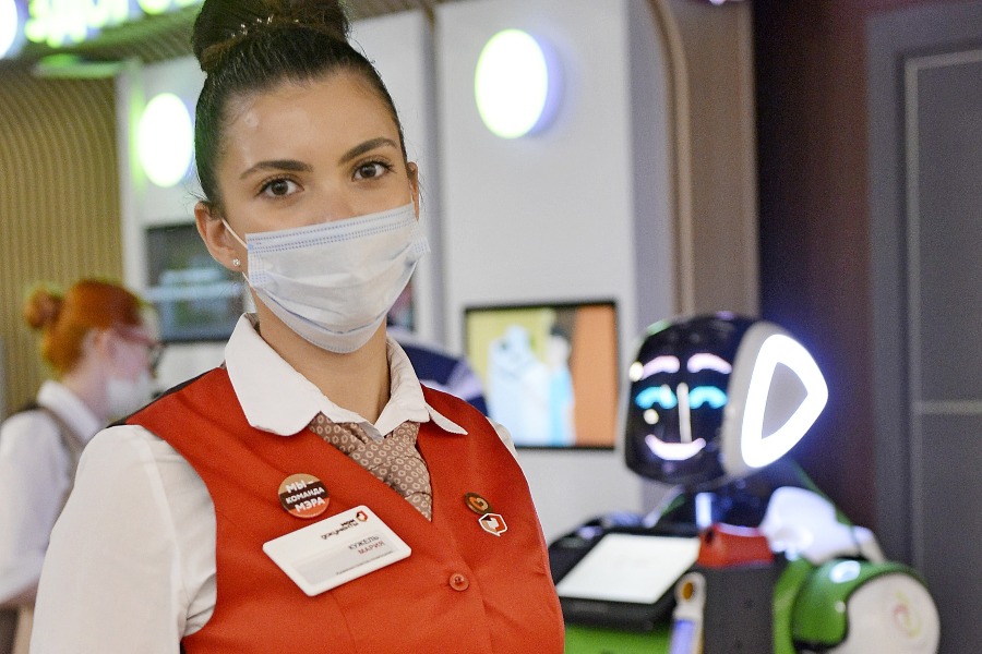 Администратор центра госуслуг районов Левобережный, Молжаниновский и Ховрино Мария Кужель и робот-диагност «Здоровкин» встречают посетителей во флагманском офисе центра госуслуг «Мои документы» в ЮАО