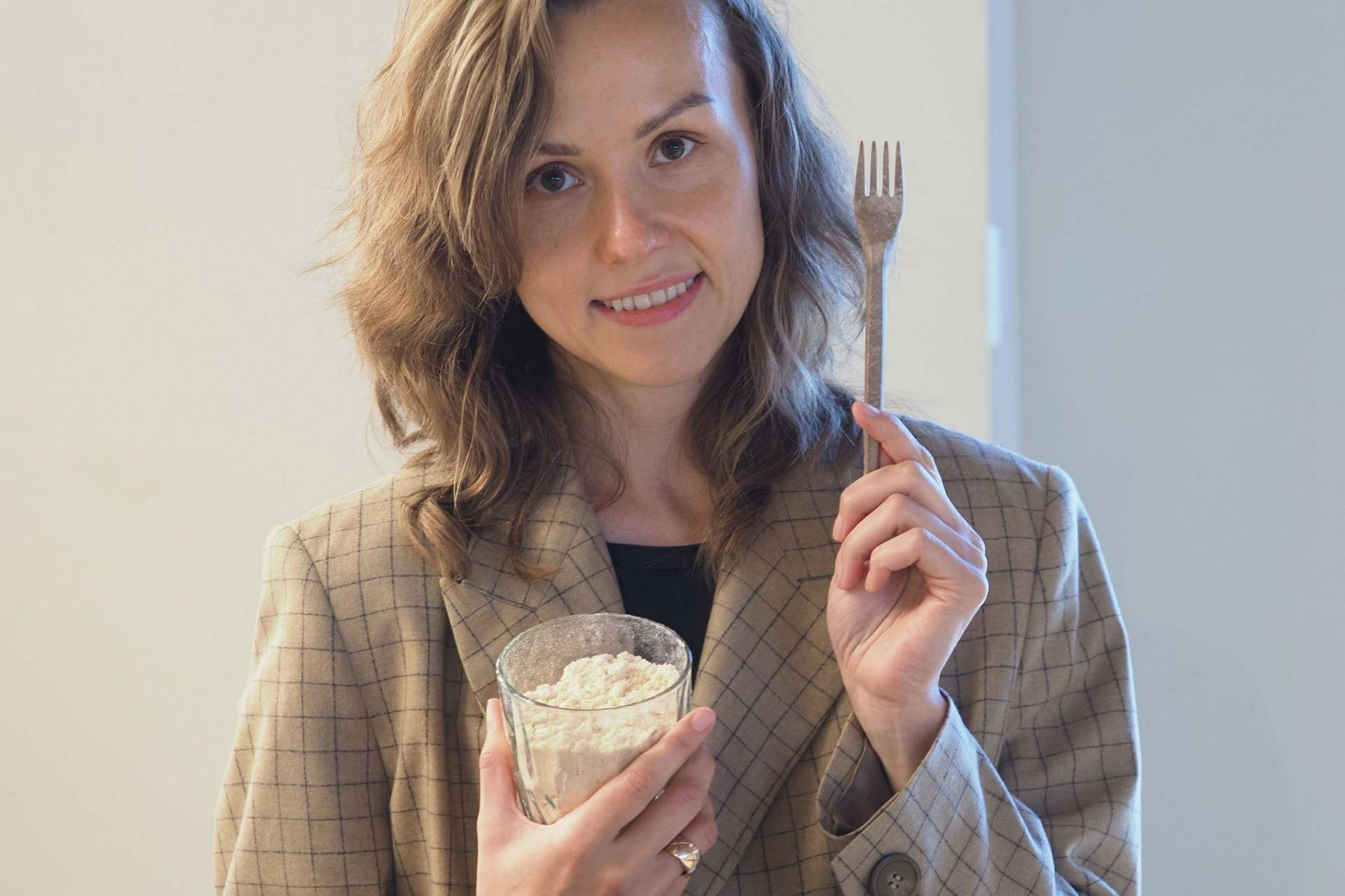 На выставке форума «Обращение с отходами» представлена продукция из вторсырья. Гендиректор одной из компаний Катерина Березина показывает стакан опилок и продукт их переработки — вилку