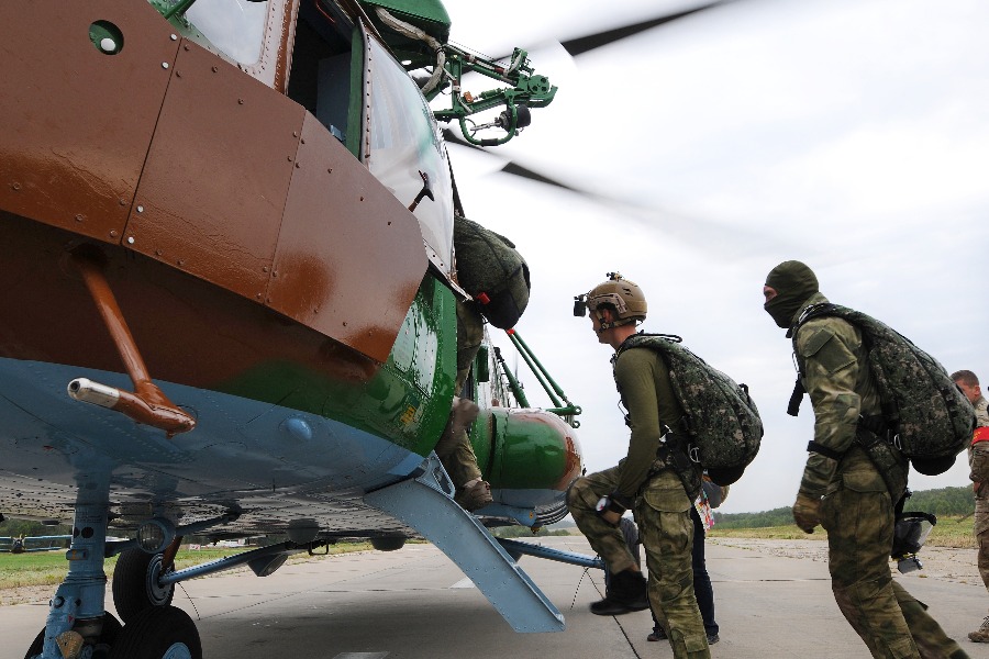 Росгвардейцы — участники учений готовятся к погрузке на вертолет. Помимо парашютов, бойцы несут с собой специальные контейнеры, где хранится необходимое для выполнения задачи снаряжение, еда, одежда и лекарства