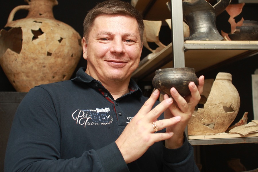 Археолог Сергей Малых показывает отреставрированный чернолощеный кувшин