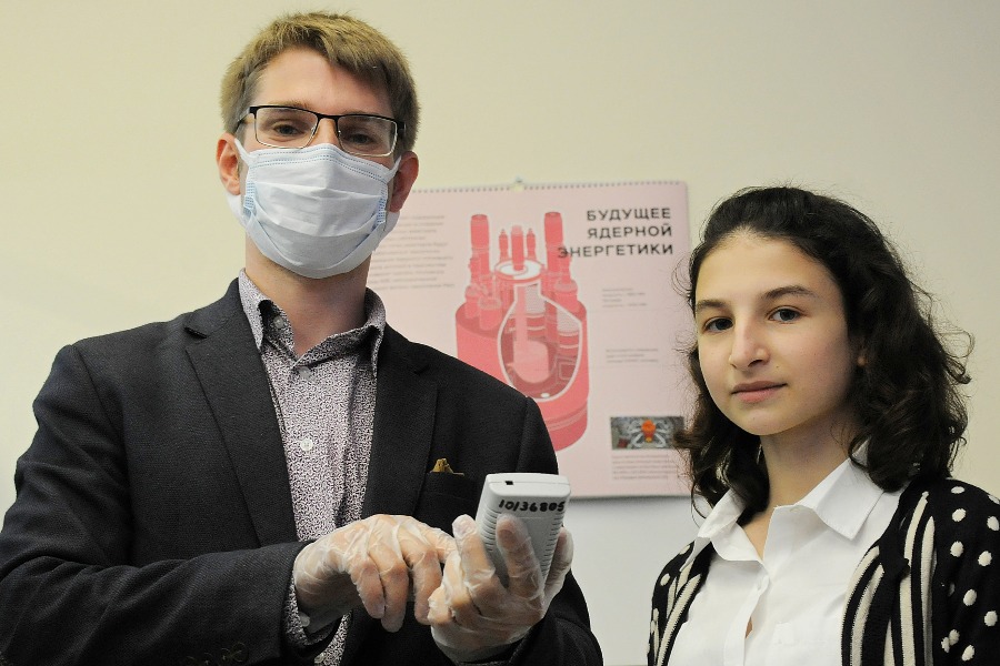 Учитель физики школы № 1547 Эрик Кекконен объясняет ученице 10-го атомного класса Марии Бос, как измеряют радиацию дозиметром. Полученные с помощью прибора данные школьница сможет использовать в своем исследовательском проекте