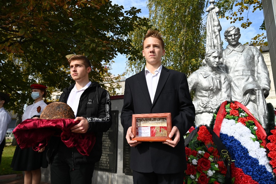 Школьники Армен Виробян (слева) и Николай Каргаев держат вещи, найденные рядом с погибшим солдатом: каску, именной медальон и документы