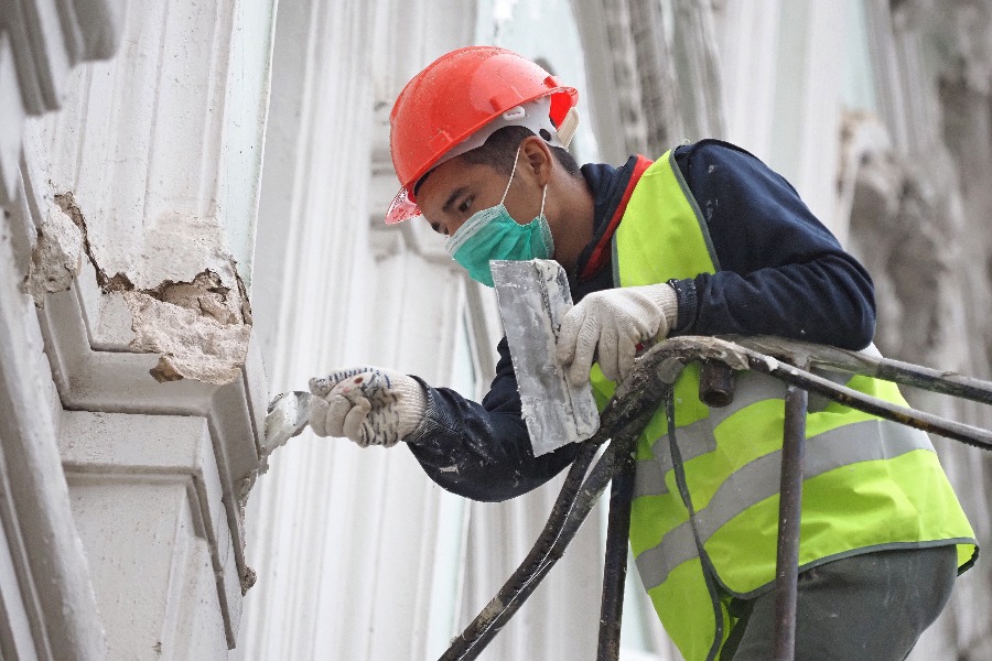 Шпаклевщик Шах Ибрагимов приводит в порядок фасад здания в Даевом переулке в центре столицы