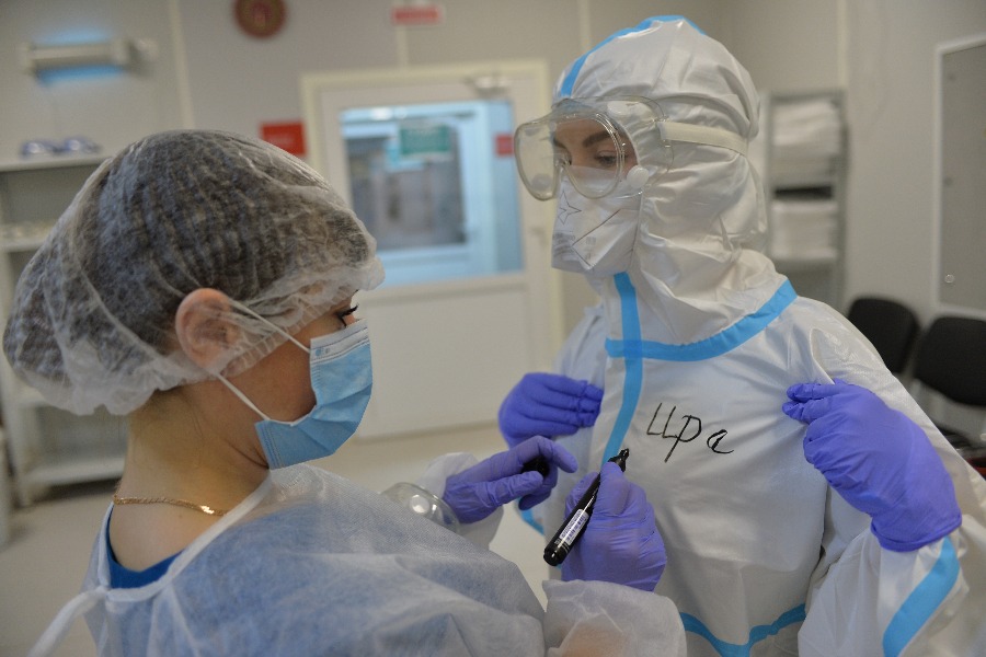 Старшая смены Ирина Салыкина (справа) надевает защитный костюм, чтобы пойти в «красную зону»