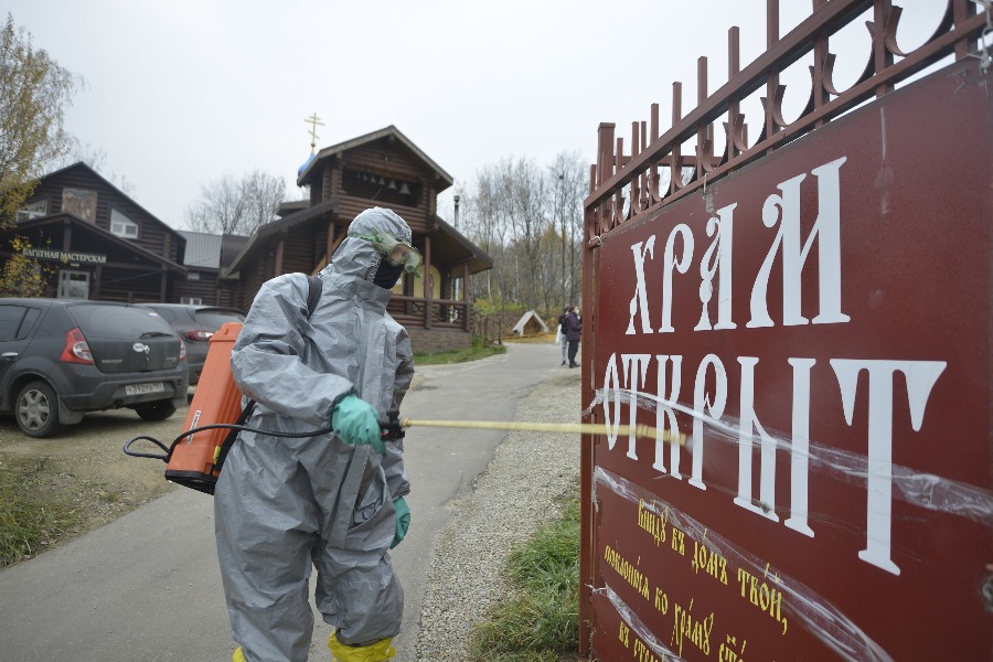 Сотрудник пожарно-спасательной части № 38 Иван Белоусов с помощью аппарата «Патриот» обрабатывает дезинфицирующим раствором информационную табличку на входе в храм