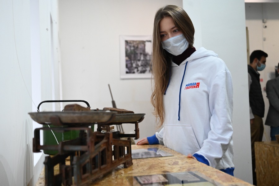 Москвичка Ксения Зайцева на одной из выставок международного проекта Измайловского кремля смотрит на весы, отмеряющие «блокадную норму» хлеба
