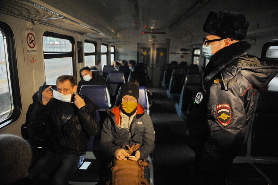 Сотрудник линейного управления МВД России на станции Москва-Курская старший сержант полиции Сергей Шокоров просит пассажира Никиту Кондратьева (крайний слева) надеть средства индивидуальной защиты: маску и перчатки