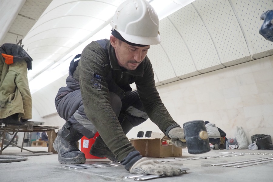 Рабочий Сергей Гончаров устанавливает тактильную навигацию на полу в переходе между «Петровским парком» и «Динамо»