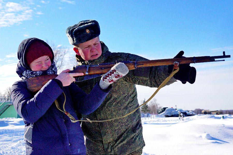 Семиклассница Мария Кириченко впервые пробует стрелять из «бабушкиной винтовки» — трехлинейки времен Великой Отечественной войны. Правильно держать оружие и целиться в мишень девочку учит лейтенант Евгений Васкевич