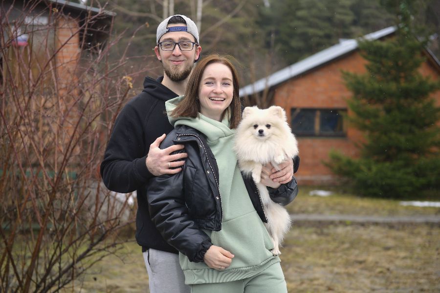 Михаил и Наталья Китаевы выгуливают шпица Баффи на территории около своего дома в поселении Воскресенское