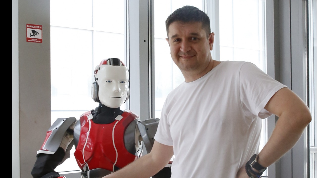 Победитель премии «Прорыв года» предприниматель Александр Кузнецов пожимает руку одному из роботов, которые производят в его компании