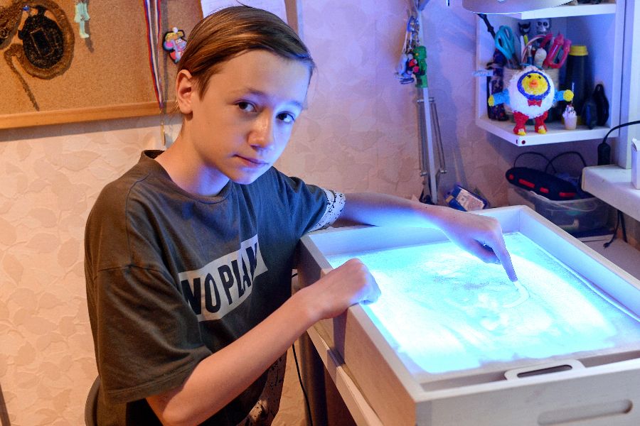 Ученик школы № 1415 Дмитрий Черняков демонстрирует свой стол для песочной анимации. Здесь он рисует сцены мультфильма и фотографирует их