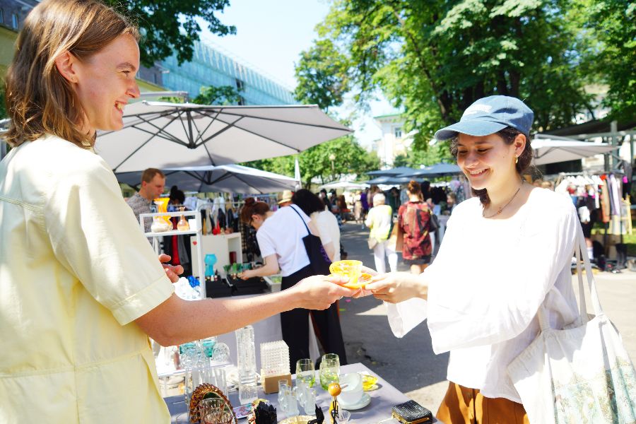 Москвичка Луна Родригез (справа) покупает у Марии Логиновой винтажную яркую чашку с блюдцем в сквере около Музея декоративно-прикладного искусства