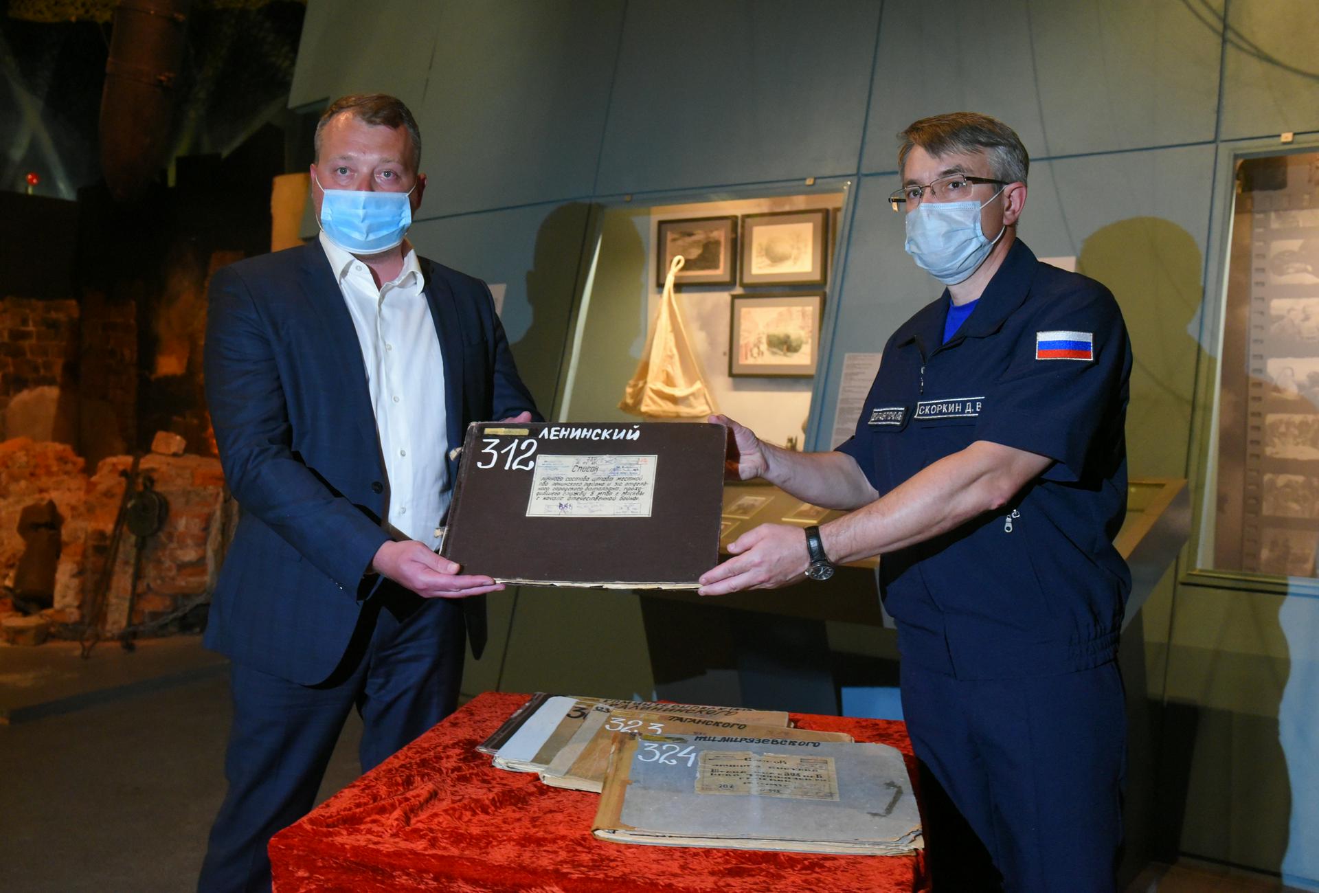 Заместитель руководителя Департамента ГОЧСиПБ Дмитрий Скоркин (справа) вручает архивные документы заместителю начальника Главархива Москвы Антону Курдакову