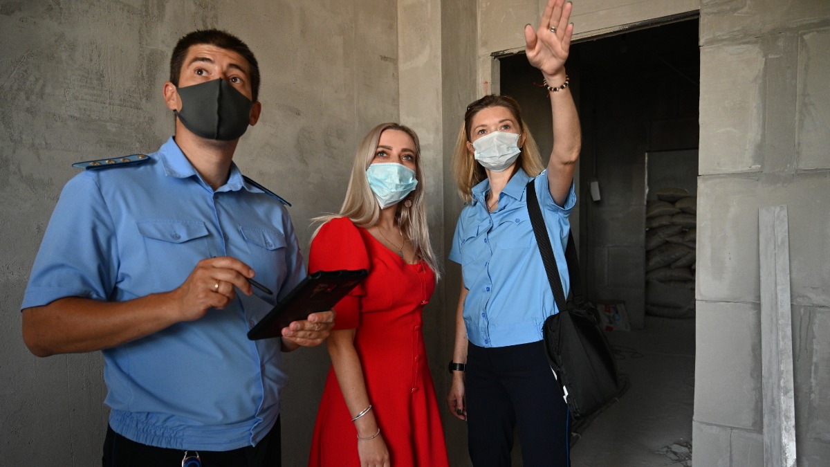 Начальник жилищной инспекции по Западному округу Москвы Артем Комаров и инспектор Екатерина Михалькова (справа) указывают собственнице квартиры в доме на Мосфильмовской улице Надежде Антоновой на нарушения, допущенные при перепланировке