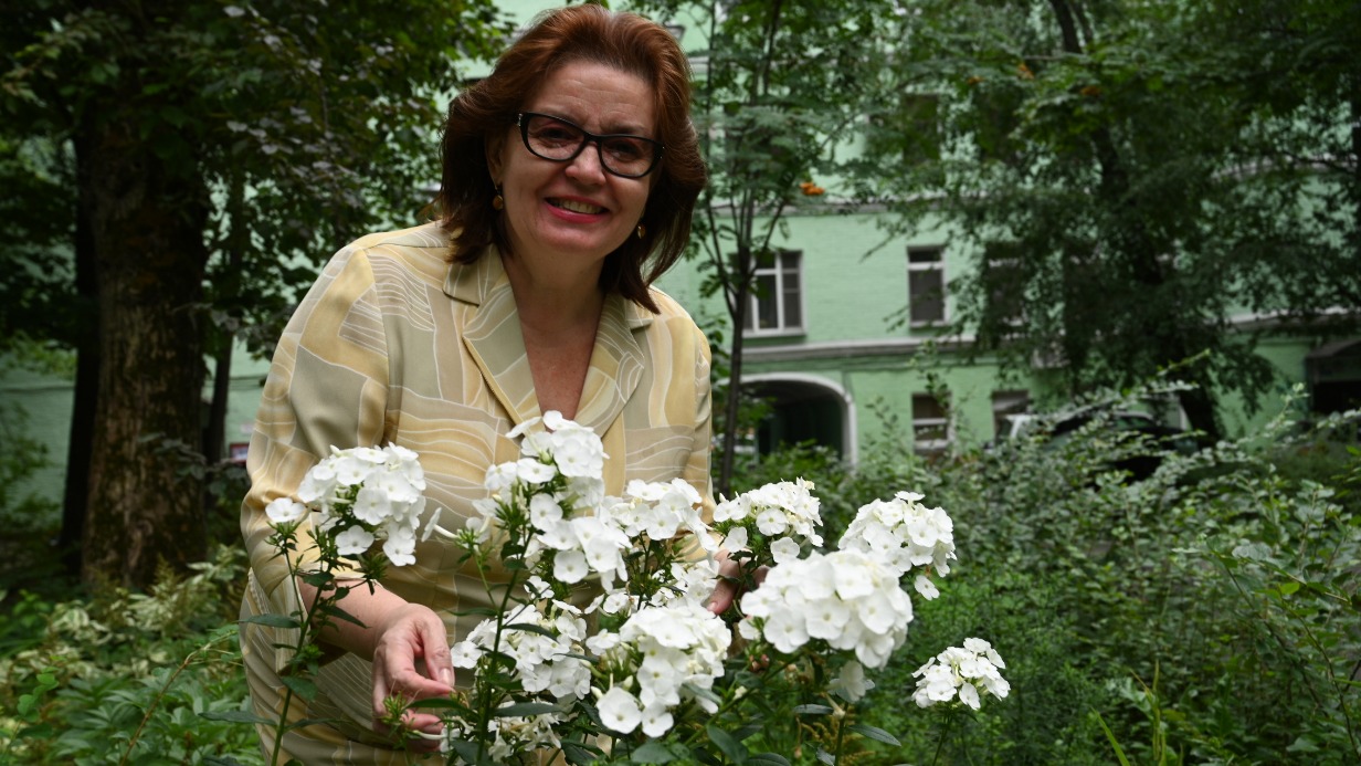 Жительница дома № 16 в Богоявленском переулке Марина Бадюл показывает белоснежные флоксы, цветущие в палисаднике во дворе