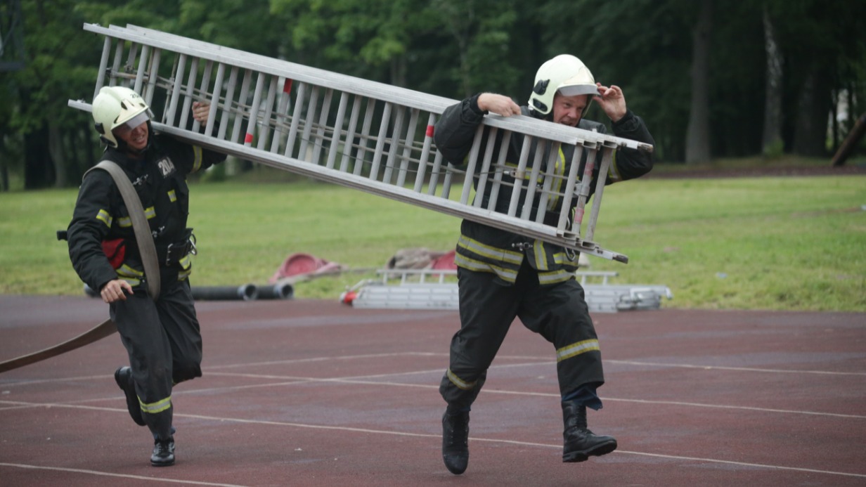 Пожарные 204-го пожарно-спасательного отряда Андрей Кобзев (слева) и Дмитрий Монахов несут раздвижную лестницу к учебной башне