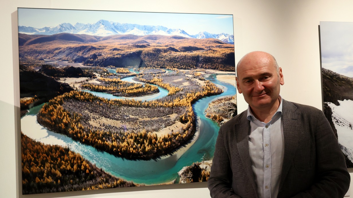 Фотограф Саша Генцис рядом с пейзажем Горного Алтая