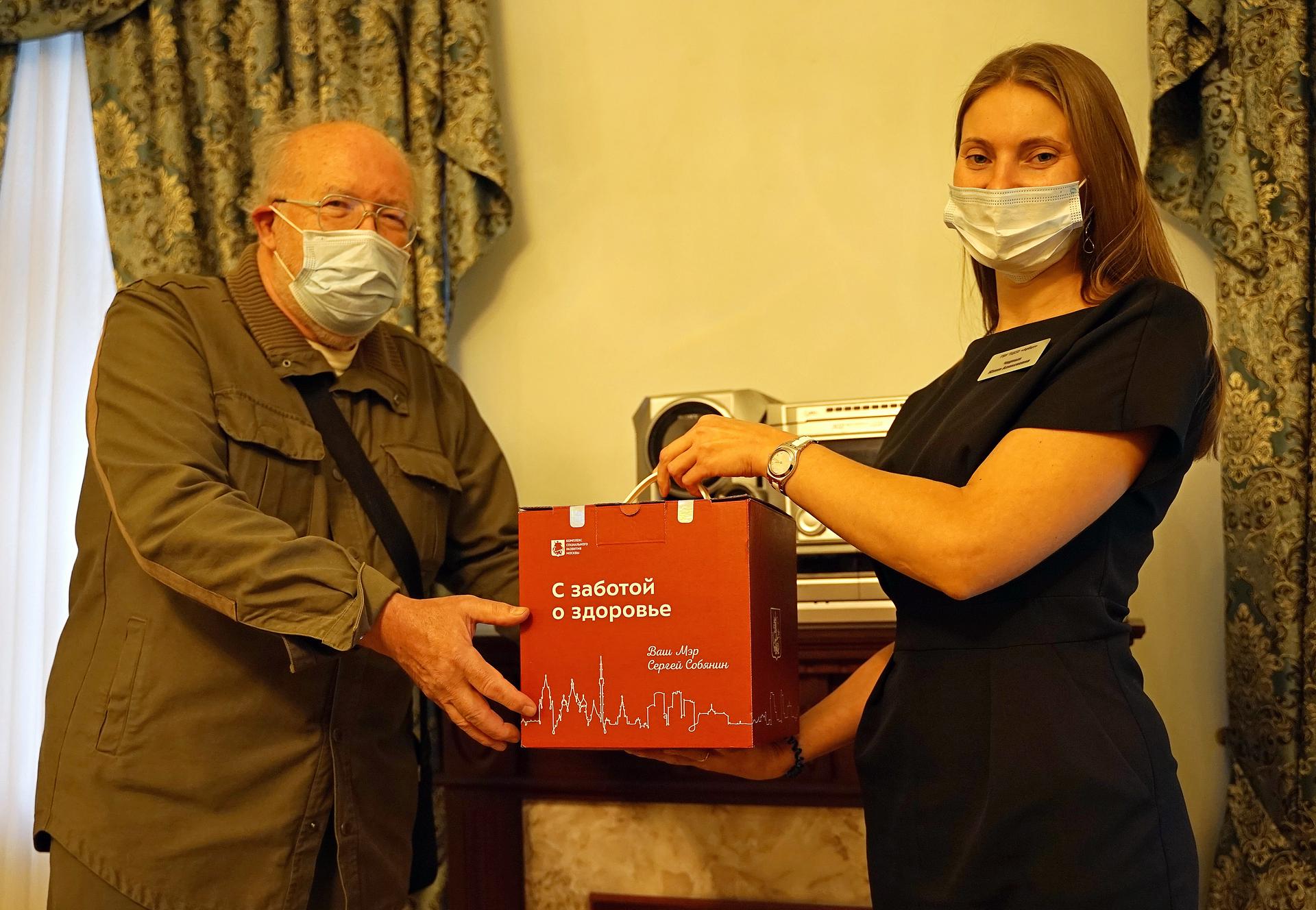 Завотделением срочного социального обслуживания ТЦСО «Арбат» Юлия Черных вручает пенсионеру Олегу Кислову коробку «С заботой о здоровье»