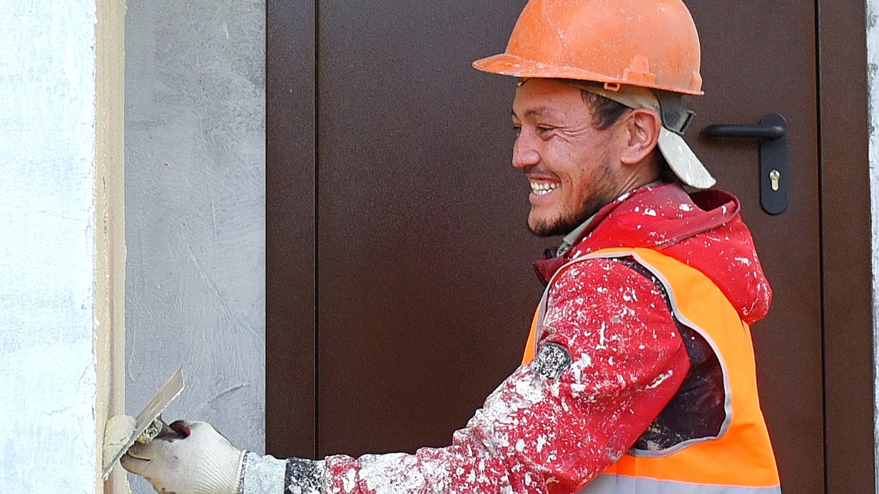 Рабочий Турусбек Сапаров штукатурит стены одного из подъездов дома