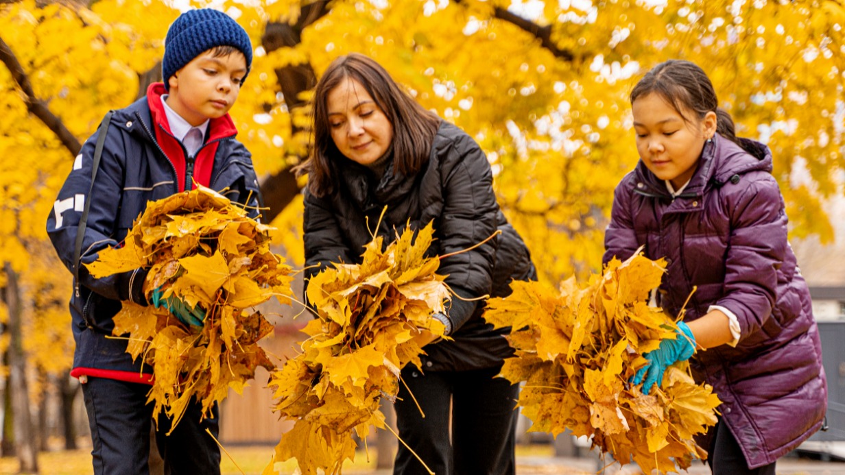 Соцпедагог школы № 2055 Ирина Дмитриева собирает листья с учеником Денисом Поповым