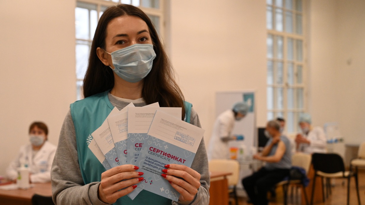 Социальный помощник Наталья Пасютина помогает москвичам в пункте вакцинации на ВДНХ. В руках она держит сертификаты, которые выдают всем после первой прививки от коронавируса