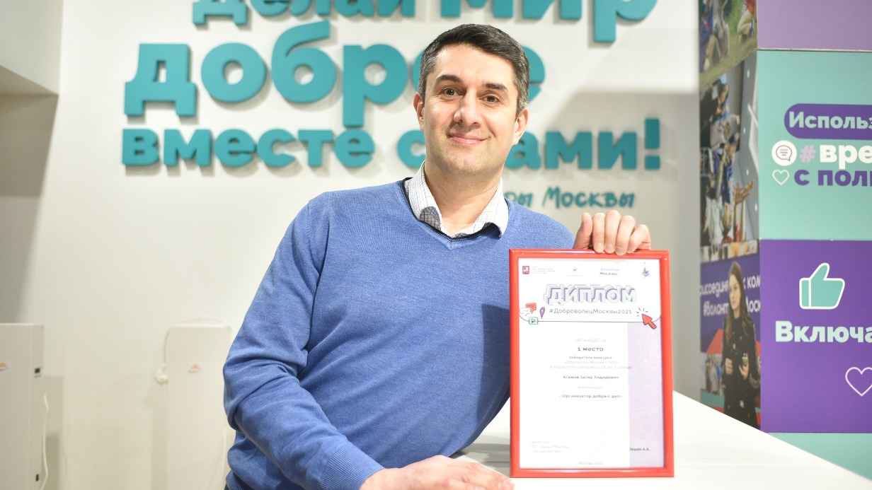Победитель конкурса «Доброволец Москвы — 2021» Загир Агамов держит диплом, который ему вручили за первое место в номинации «Организатор добрых дел». Он работает врачом в поликлинике, а в свободное время проходит бесплатные занятия по оказанию первой помощи в рамках своего проекта «Спаси ближнего»