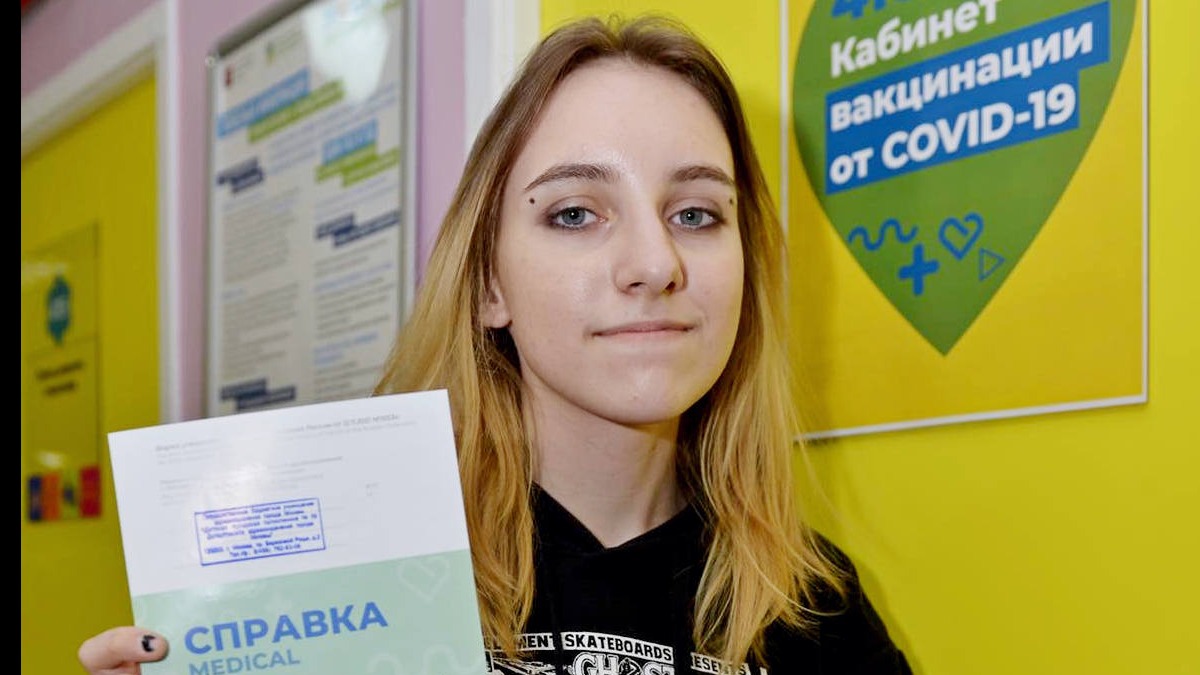 Школьница Полина Русанова держит в руках справку о вакцинации от новой коронавирусной инфекции. Прививку она сделала в детской поликлинике № 39